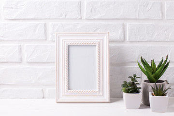 Empty frame mockup and succulents and cactus plants in pots  near by white brick wall.
