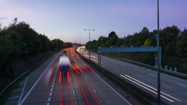Time lapse view of a busy expressway with light trails during a sunset.