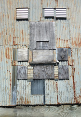 Old rusty corrugated steel and plywood patchworked wall