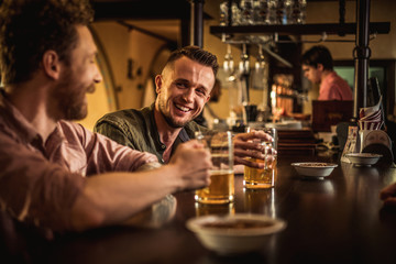 Cheerful friends drinking draft beer in a pub