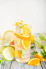 Summer refreshment drinks. Four types of citrus lemonade or mojito cocktail - orange, lime, lemon, pink grapefruit. Infused citrus water. On a wooden white background,