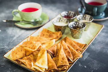 Breakfast on the table with pancakes, sour cream, honey, jam and tea