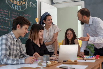 Smiling coworkers standing in front of the table during presentation. Young coworkers standing in office and discussing and smiling