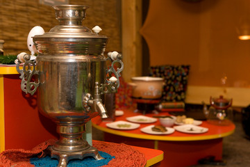 Obraz na płótnie Canvas Traditional samovar in the interior of rich colors, on the background of a table. Oriental, Asian styles.