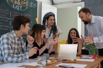 Smiling co workers standing in front of the table during presentation. Young co workers standing in office and discussing project