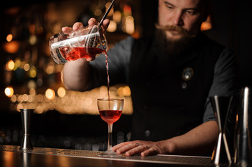 Male bartender makes an alcohol drink with strainer