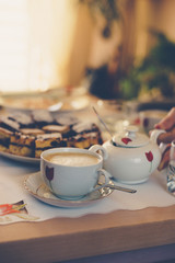 Warm coffee in a cup and cake on the table. Retro stylized photo. 