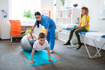 Hard-working little boy leaning on a grey pilates ball