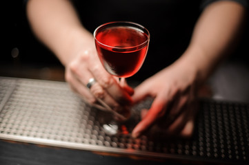 Alcohol drink with cherry in bartender's hands