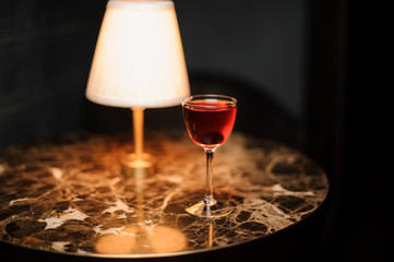 Alcohol drink with cherry on table with lamp