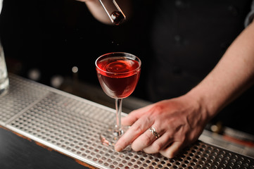 Bartender adding cherry in an alcohol drink