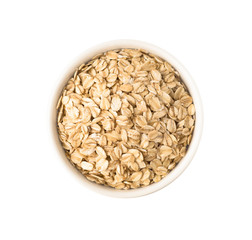 Top view uncooked oat flakes in round ceramic plate. Raw food ingredient isolated on white background