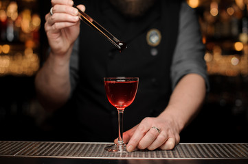 Close-up of bartender dropping cherry in alcohol drink