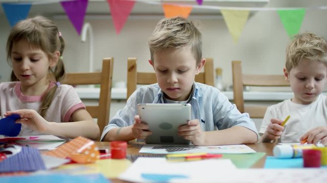 children make preparation for fiesta while one of them play in the tablet