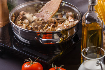 young woman in a gray apron roasts mushrooms in a frying pan