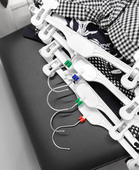 white hangers with clothes lie on a black cabinet in the dressing room of the store. Close-up, top view.