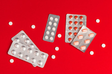 Pills in blisters on red background top view. Medicine