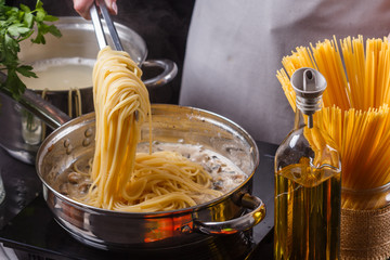 young woman in a gray apron preparing pasta