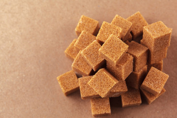 Brown cane sugar cubes on a light brown background