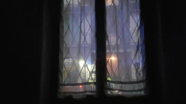 Static shot, view thru window with curtains, ambulance - police - fire engine blue and red lights