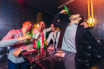 Group of smiling male friends having fun in night club - obrazy, fototapety, plakaty