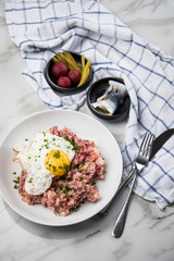 Norddeutscher Hamburger Labskaus mit Rindfleisch Corned Beef, Rote Beete, Kartoffeln, Saure Gurken, Spiegelei und Rollmops auf Teller