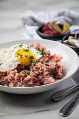 Norddeutscher Hamburger Labskaus mit Rindfleisch Corned Beef, Rote Beete, Kartoffeln, Saure Gurken, Spiegelei und Rollmops auf Teller