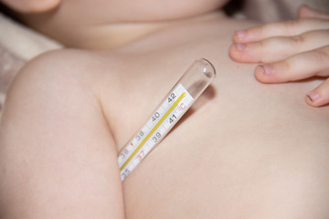 The boy measures the temperature of a mercury thermometer. the boy is sick