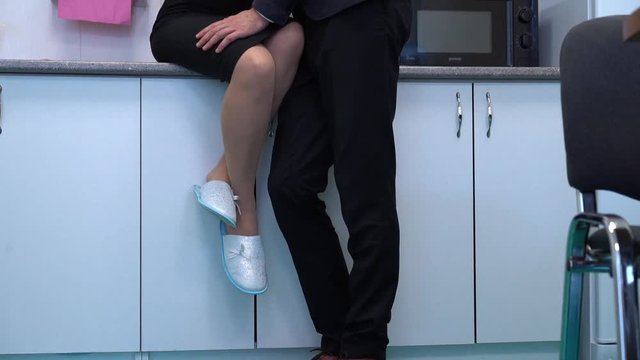 Businessman is flirting with businesswoman in the work's kitchen.