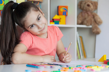 Happy cute child girl sitting at a table and drawing. Developmental activities. Back to school and happy time!