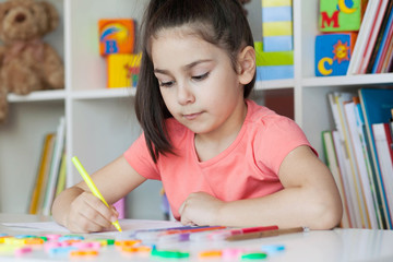 Happy cute child girl sitting at a table and drawing. Developmental activities. Back to school and happy time!