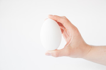 Fototapeta na wymiar holds in his hand a large white egg on a white background