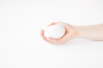 Fototapeta na wymiar holds in his hand a large white egg on a white backgroundм