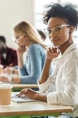 African American student sitting at desk with notebook and cup of coffee