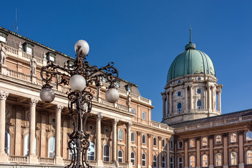 Hungary, Budapest, Buda, Hunyadi Udvar: Famous facade of Royal Palace at Castle Hill district above the city center of the Hungarian capital with vintage lantern and blue sky - concept architecture.