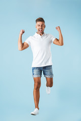 Excited emotional adult man posing isolated over blue wall background make winner gesture.