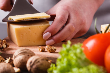 young woman slicing cheese in a gray apron