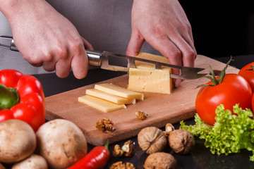 young woman slicing cheese in a gray apron