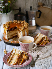 Carrot cake with salted caramel and cheesecake inside, decorated with popcorn and caramel. A slice of cake with a cup of coffee, retro style, vintage. Selected focus, close up