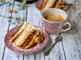 Carrot cake with salted caramel and cheesecake inside, decorated with popcorn and caramel. A slice of cake with a cup of coffee, retro style, vintage. Selected focus, close up