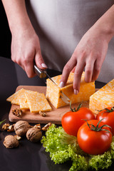 young woman slicing cheese in a gray apron