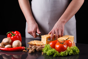 young woman slicing cheese in a gray apron