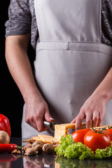 young woman slicing cheese in a gray apron