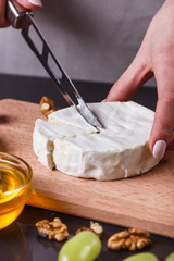 young woman slicing cheese in a gray apron