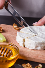 young woman slicing cheese in a gray apron