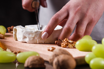 young woman slicing cheese in a gray apron