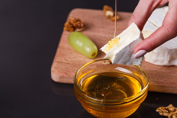 a young woman in a gray apron pouring honey Camembert cheese