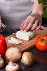 young woman slicing cheese in a gray apron