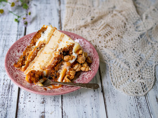 Carrot cake with salted caramel and cheesecake inside, decorated with popcorn and caramel. A slice of cake, retro style, vintage. Selected focus, close up, copy space.