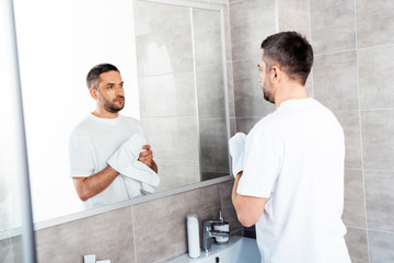 Fototapeta premium handsome man wiping hands with towel in bathroom during morning